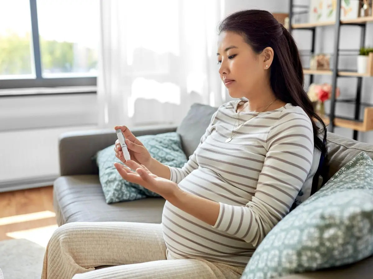 Gestational diabetes testing: Pregnant woman checking blood glucose levels with a lancing device.